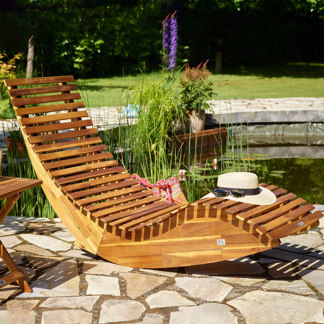 Lammeuld liggestole og havesenge i akacietræ og aluminium opstillet på en lys flisebelagt terrasse i lifestyle-stil med parasol over