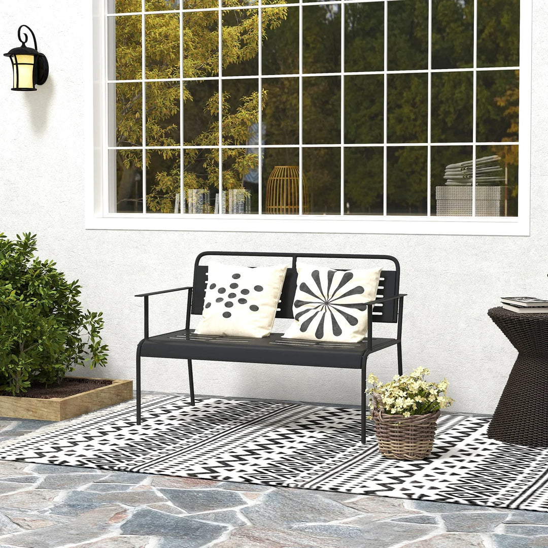 Sort metal havebænk på terrasse med pillows, taepper og potteplanter, lifestyle scene udendørs